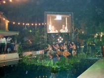 Opening ceremony for the Swire Research Station, when a cultural group is dancing on a platform floating in a pool of the Gateway Hotel in Port Moresby, under the image of the Wanang conservation leader Filip Damen projected on the screen.